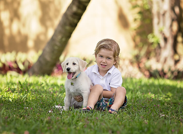 boy and puppy sitting on grass together