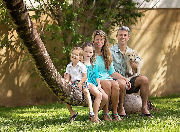 Family posing on tree with new puppy