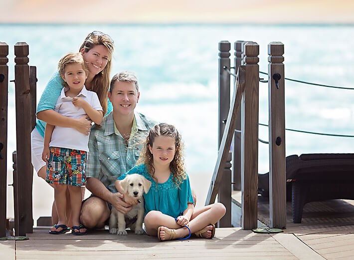 Family posing with new puppy with the beach in the background