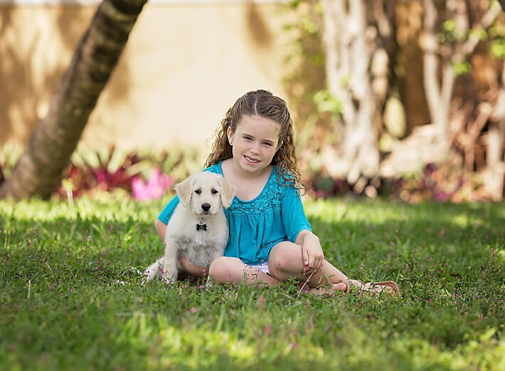 Girl and puppy sitting on grass together