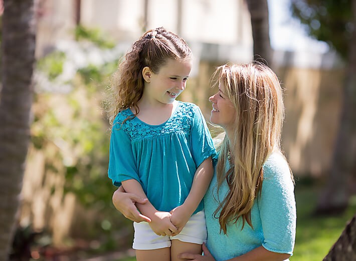 Mom and daughter looking at each other for their outdoor portrait