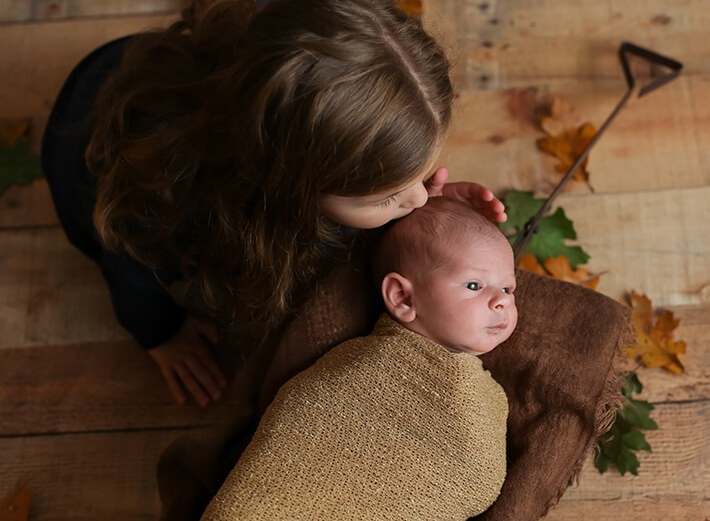 Big sister kissing her baby brother