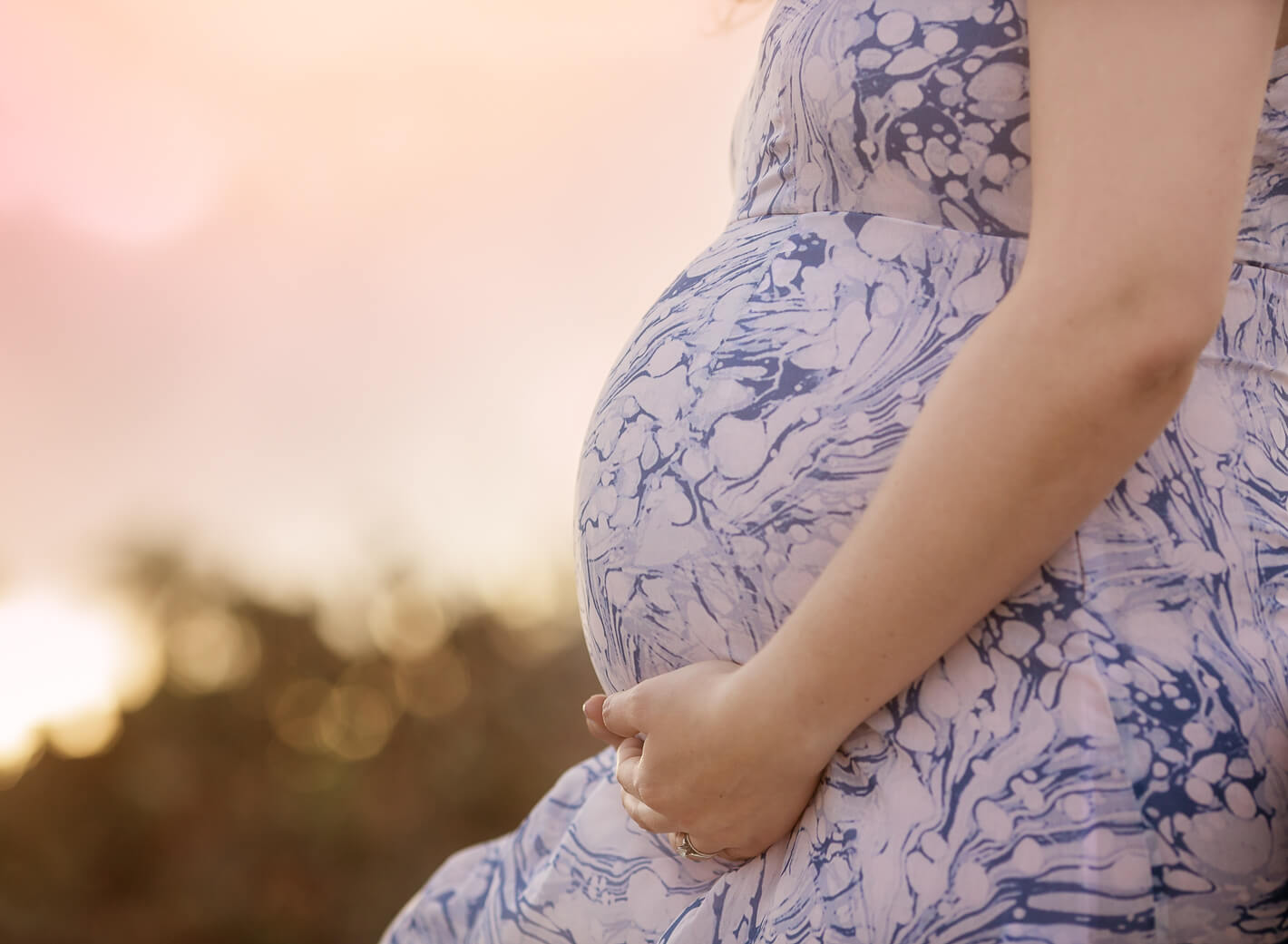 Closeup of pregnant belly during sunset