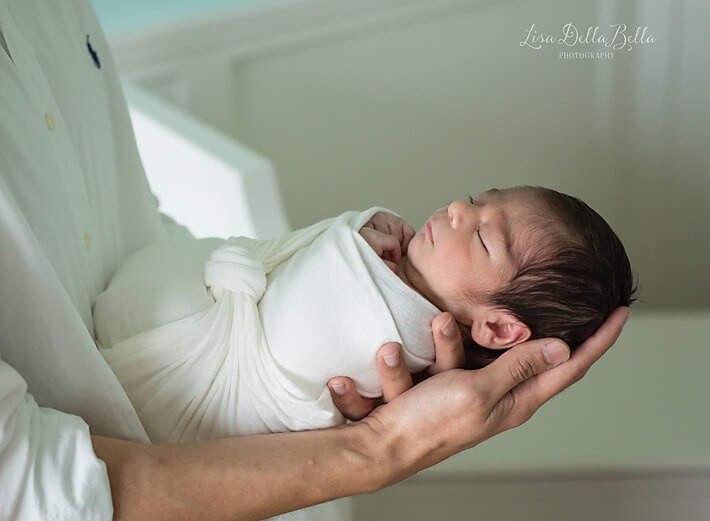 Newborn posed in dad's arms